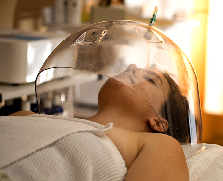 A woman with an oxygen dome over her face receiving an organic skin therapy oxygen facial at Natural Balance Massage Therapy & Wellness Center in Palm Harbor, Florida.